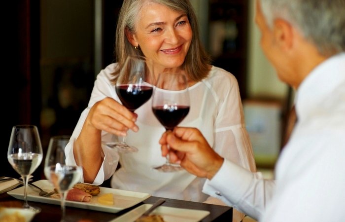 Portrait of elderly woman toasting wine with her husband at restaurant